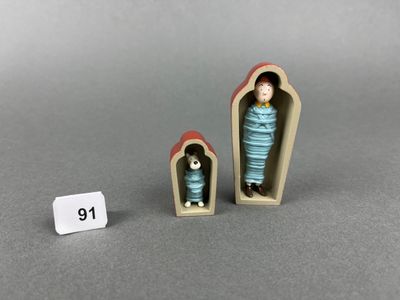 two miniature figurines of a woman and a cat in a coffin