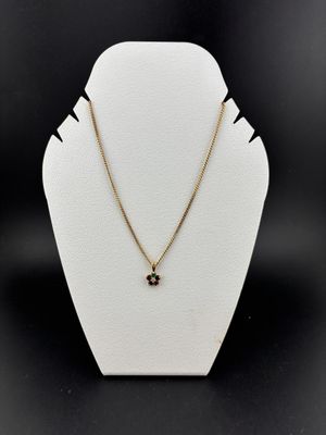 a white mannequin with a gold chain and a black diamond pendant