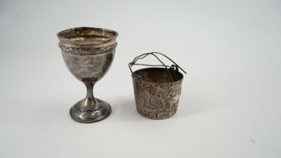 une coupe en argent à côté d'une autre coupe en argent, posées sur une surface blanche