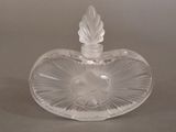 a clear glass heart shaped bottle with a leaf on it