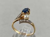 a close up of a gold ring with a sapphire and a pearl