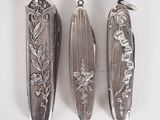 three silver spoons with flowers and leaves on them on a white surface