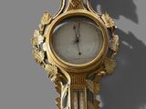 a gold clock on the wall with a shadow on the wall