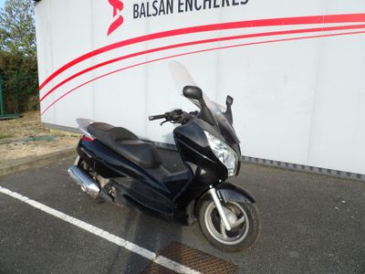 une moto noire garée sur un parking, près d'un mur