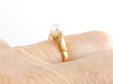 a woman ' s hand with a pearl ring on it