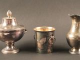 trois vases en argent posés l'un à côté de l'autre sur une table