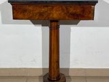 a small wooden table with a black top on a tiled floor