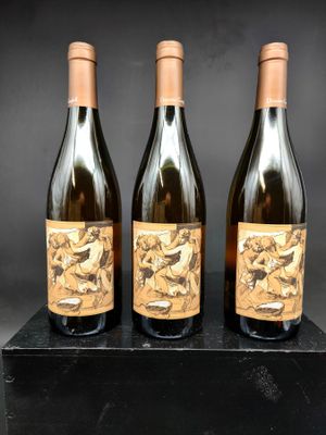 trois bouteilles de vin posées sur un bloc de marbre noir