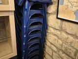 des chaises en plastique bleues empilées les unes sur les autres devant un mur de briques