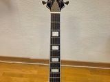 a black acoustic guitar sitting on top of a hard wood floor