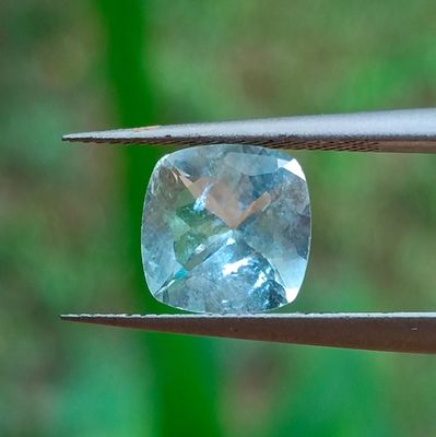 un gros plan d'un diamant bleu tenu par une paire de pinces