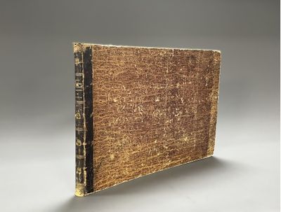 un vieux livre posé sur une table à côté d'un mur gris