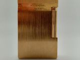 une photo d'un briquet doré posé sur une table blanche