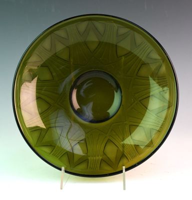 un bol en verre vert à bord noir, posé sur un socle