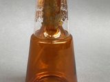 a brown glass bottle with a gold lid on a gray surface