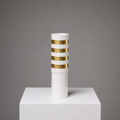 un vase blanc et doré posé sur un socle blanc
