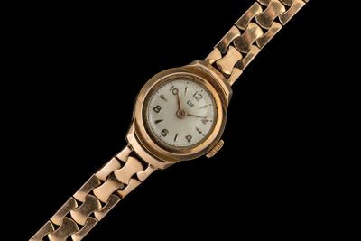a gold wrist watch with a white face on a black background
