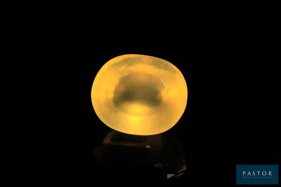 a close up of a yellow glass ball on a black surface