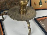 a gold plate with a candle on it next to framed pictures