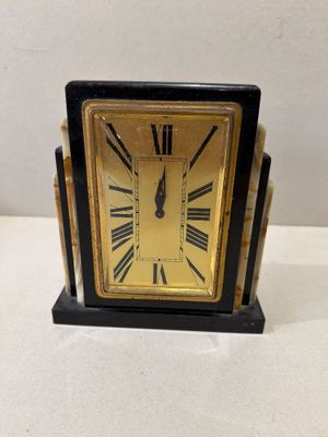 une horloge noire et dorée avec des chiffres romains