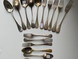 many spoons and forks laid out on a table