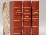 three red books sitting on top of each other on a white surface