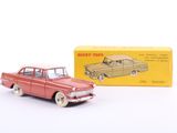 une petite voiture rouge à côté d'une boîte jaune sur une surface blanche