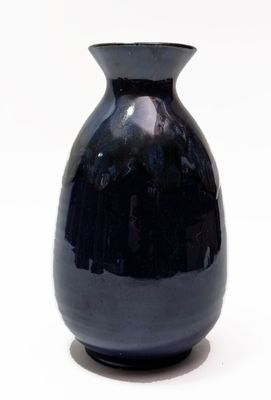un vase noir posé sur une surface blanche
