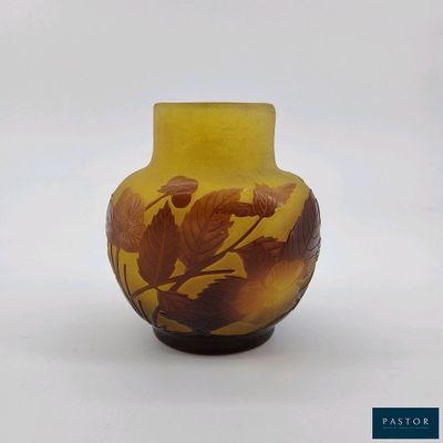 un vase jaune orné de feuilles, posé sur une surface blanche