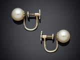 a pair of pearl and gold earrings on a black background