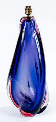 un vase en verre bleu avec un couvercle doré, posé sur une surface blanche