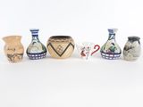 cinq vases alignés sur une surface blanche