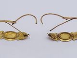 pair of gold earrings with oval stones on them on a white surface