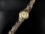 a close up of a gold watch on a black surface