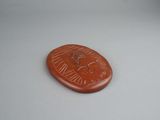 a small red stone coin with an image of a bird on it