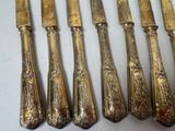 six antique silverplated flatware knives and a knife on a white surface