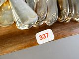 de nombreuses cuillères en argent posées sur une étagère, accompagnées d'une étiquette de prix