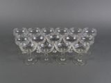 six clear wine glasses lined up in a row on a gray surface