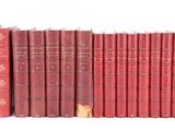 Plusieurs livres rouges sont alignés sur une surface blanche