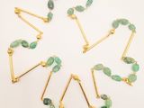 a close up of a necklace with green beads on a white surface