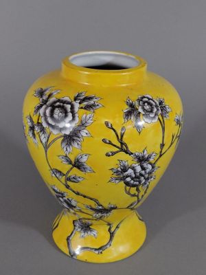 un vase jaune orné de fleurs noires et blanches