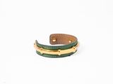 un gros plan d'un bracelet en cuir vert sur fond blanc