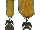 deux médailles et une bague ornée d'un aigle sur fond blanc