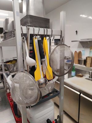 de nombreuses casseroles et poêles suspendues à une étagère dans la cuisine