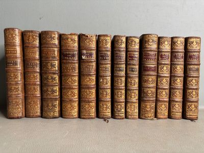 several old books are lined up on a shelf next to each other