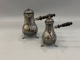 a pair of silver salt and pepper shakers on a white surface