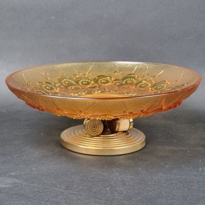 a glass bowl on a gold stand on a gray surface