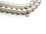 two strands of white pearls with a silver clasp on a white background