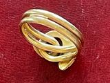 une bague en or ornée d'un nœud, posée sur un fond rouge