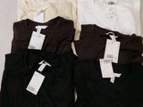 Trois t-shirts sont posés sur une surface blanche, avec leurs étiquettes encore attachées.